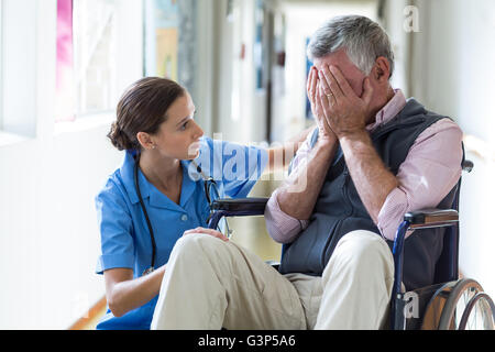 Female doctor consoling senior man in corridor Stock Photo