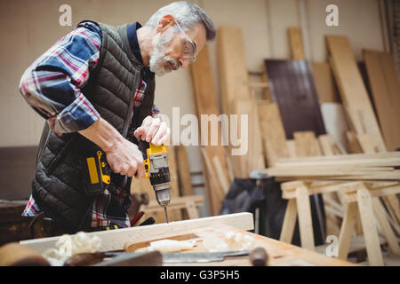 Carpenter drilling a plank of wood Stock Photo