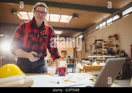 Carpenter using his smartphone Stock Photo