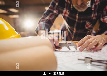 Carpenter taking measures on a plan Stock Photo