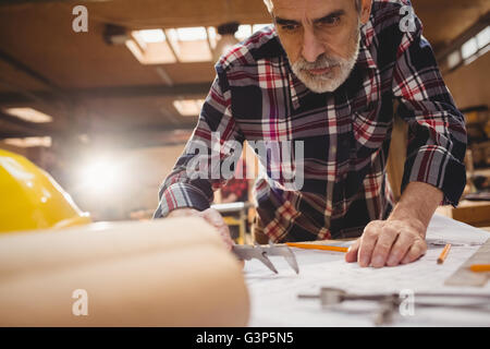 Carpenter taking measures on a plan Stock Photo