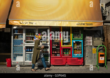 A woman in a colourful headscarf walks past a store in Safranbolu, Karabuk, Turkey Stock Photo