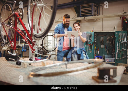Bicycle repairer colleagues looking at laptop Stock Photo