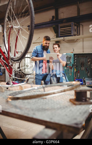 Bicycle repairer colleagues looking at laptop Stock Photo
