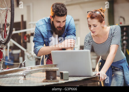Bicycle repairer colleagues looking at laptop Stock Photo