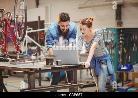 Bicycle repairer colleagues looking at laptop Stock Photo