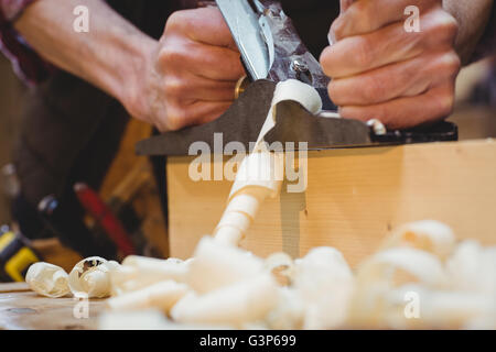 Portrait of carpenter perfecting wood plank form with a work tool Stock Photo