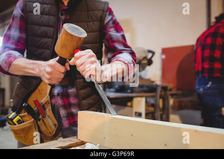 Close-up of carpenter using a mallet on a wood plank Stock Photo