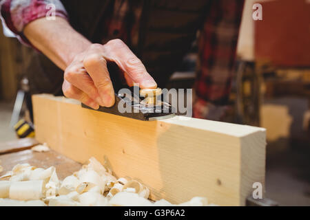 Close-up of carpenter using a sander on a wood plank Stock Photo