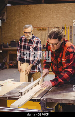 Focused duo of carpenter cutting a wood plank Stock Photo