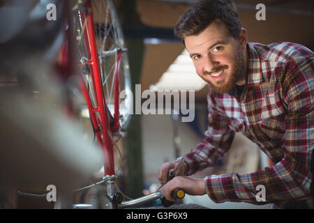 Portrait of smiling mechanic repairing a bicycle Stock Photo