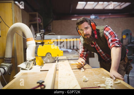 Carpenter marking on wooden plank with pencil in workshop Stock Photo