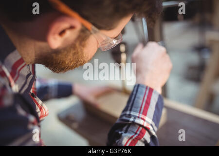 Carpenter working on a drill press machine Stock Photo