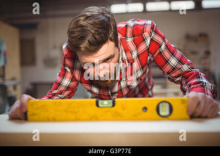 Carpenter using spirit level to measure Stock Photo