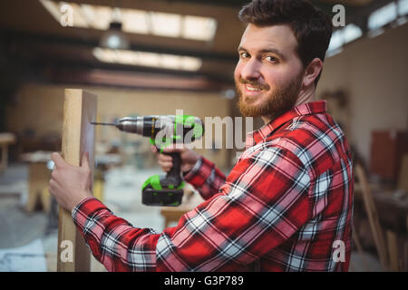 Carpenter drilling a hole in a wooden plank Stock Photo