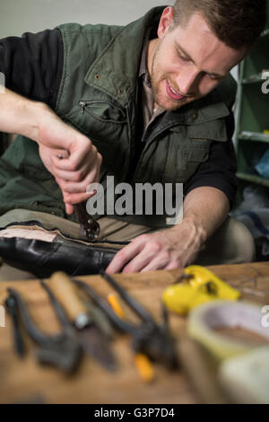 Cobbler repair shoes sole in workshop Stock Photo