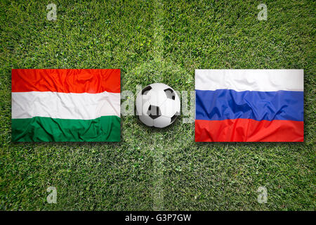Hungary vs. Russia flags on green soccer field Stock Photo