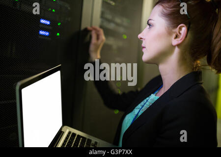 Technician using laptop while analyzing server Stock Photo