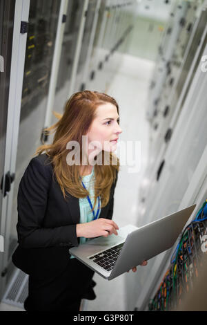 Technician using laptop while analyzing server Stock Photo
