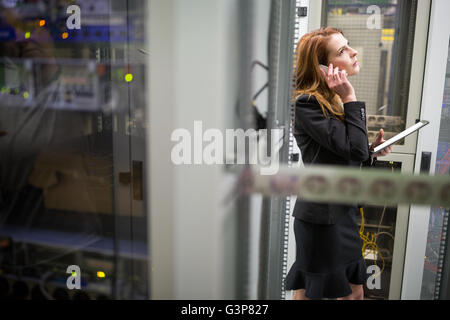 Technician holding digital tablet and talking on mobile phone Stock Photo