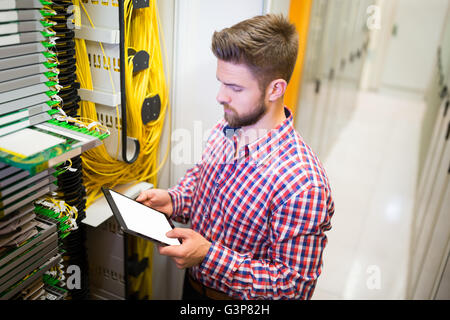 Technician using digital tablet while analyzing server Stock Photo