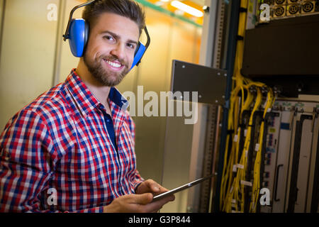 Technician in head phones using digital tablet while analyzing server Stock Photo