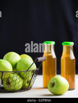 Green apples in a basket and two bottles of Apple juice. Selective focus. Stock Photo