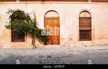 Facade of old rustic house, with washed peach colored walls at Colonia, Uruguay. Grunge style. Stock Photo