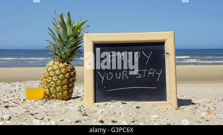 Enjoy your stay written on a chalkboard at the beach Stock Photo