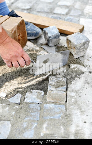 Details with hands of a mason working with cobblestone Stock Photo