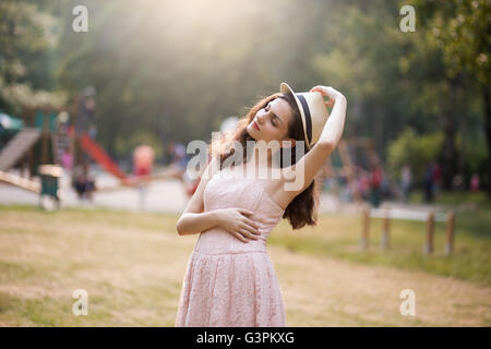 Young woman in pink dress holding her hat Stock Photo