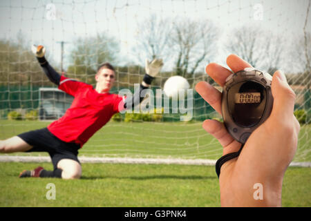 Composite image of coach is holding a stopwatch against goalkeeper Stock Photo