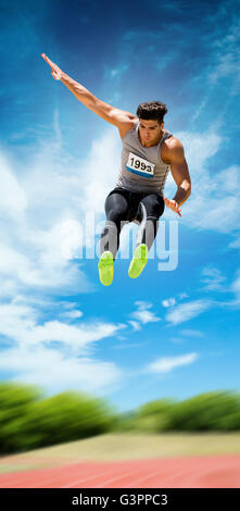 Sportsman jumping against athletics field Stock Photo