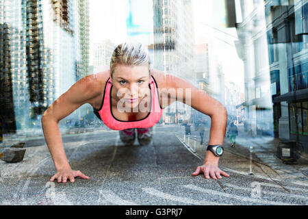 Composite image of a pretty woman doing push-ups on the floor Stock Photo