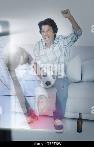 Composite image of happy man is watching sport on television Stock Photo