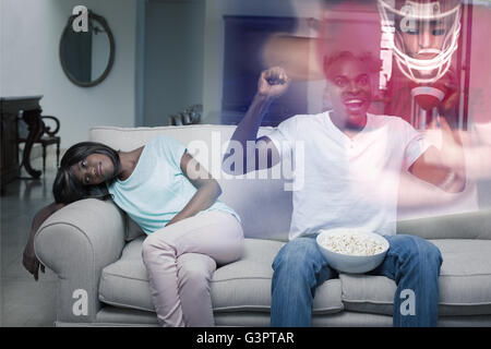 Composite image of man watching sport on television next to his bored wife Stock Photo