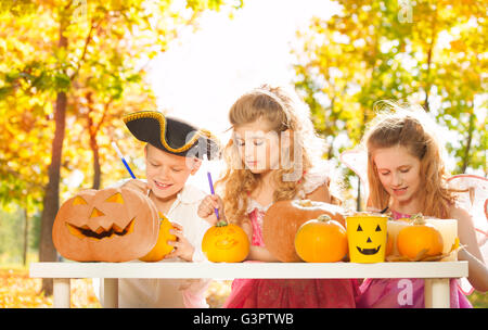 Three children during Halloween crafting pumpkins Stock Photo