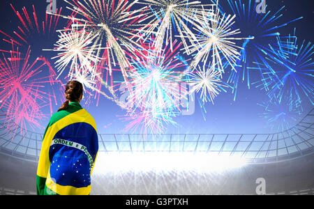 sporty woman holding the Brazilian flag against fireworks exploding over football stadium Stock Photo