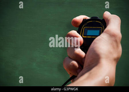 Close up of hand holding a chronometer against green chalkboard Stock Photo