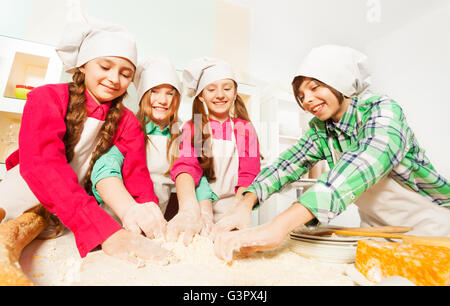 Four friends kneading bakery dough at the kitchen Stock Photo