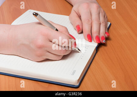Female hands with manicure over pages of a notebook Stock Photo