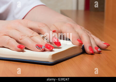 Female hands with manicure over pages of a notebook Stock Photo
