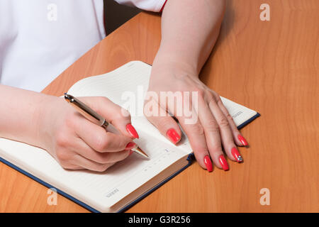 Female hands with manicure over pages of a notebook Stock Photo
