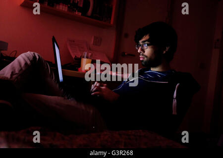 Young man studying with laptop on knee Stock Photo
