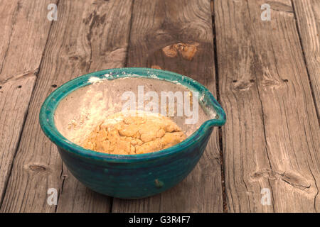 bread making series.  Bread dough rises in a bowl with a cutting board spread with flour on a rustic picnic table. Stock Photo