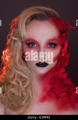 Gothic, fashion, fantasy, blonde English rose beauty portrait, red flowers, leaves, creative make-up Stock Photo