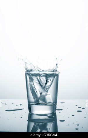 Ice cube falling in glass with water Stock Photo