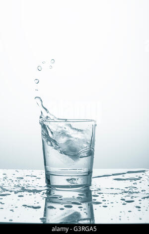 Ice cube falling in glass with water Stock Photo