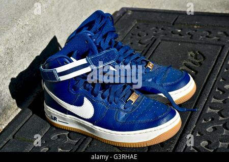 A pair of blue Nike shoes sitting on a door mat in front of a house Stock Photo