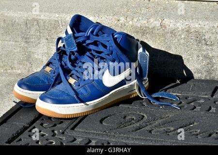 A pair of blue Nike shoes sitting on a door mat in front of a house Stock Photo